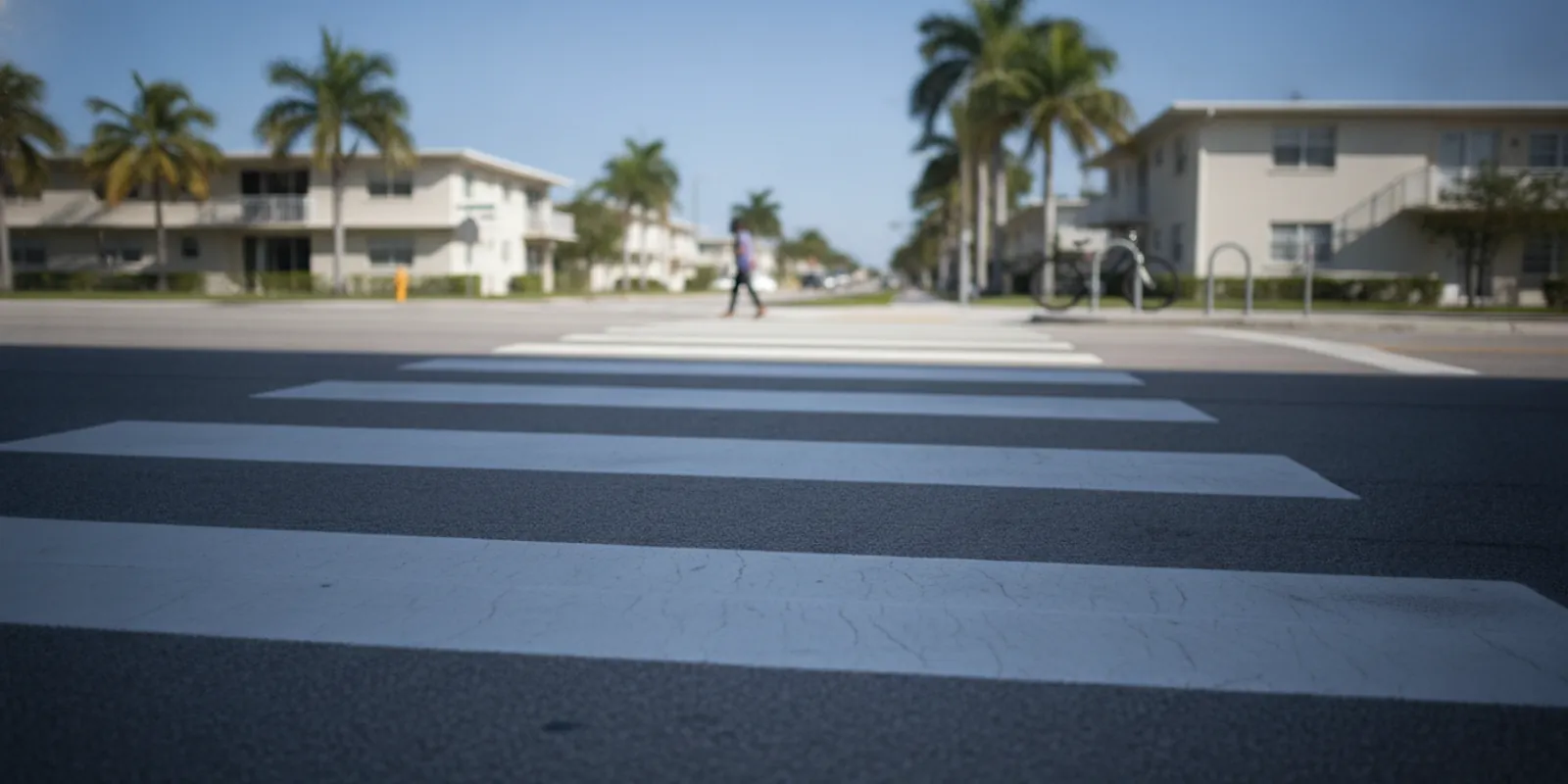 A sunny Miami crosswalk with a bicycle and a pedestrian-crossing sign — Accident Lawyer Miami Plus